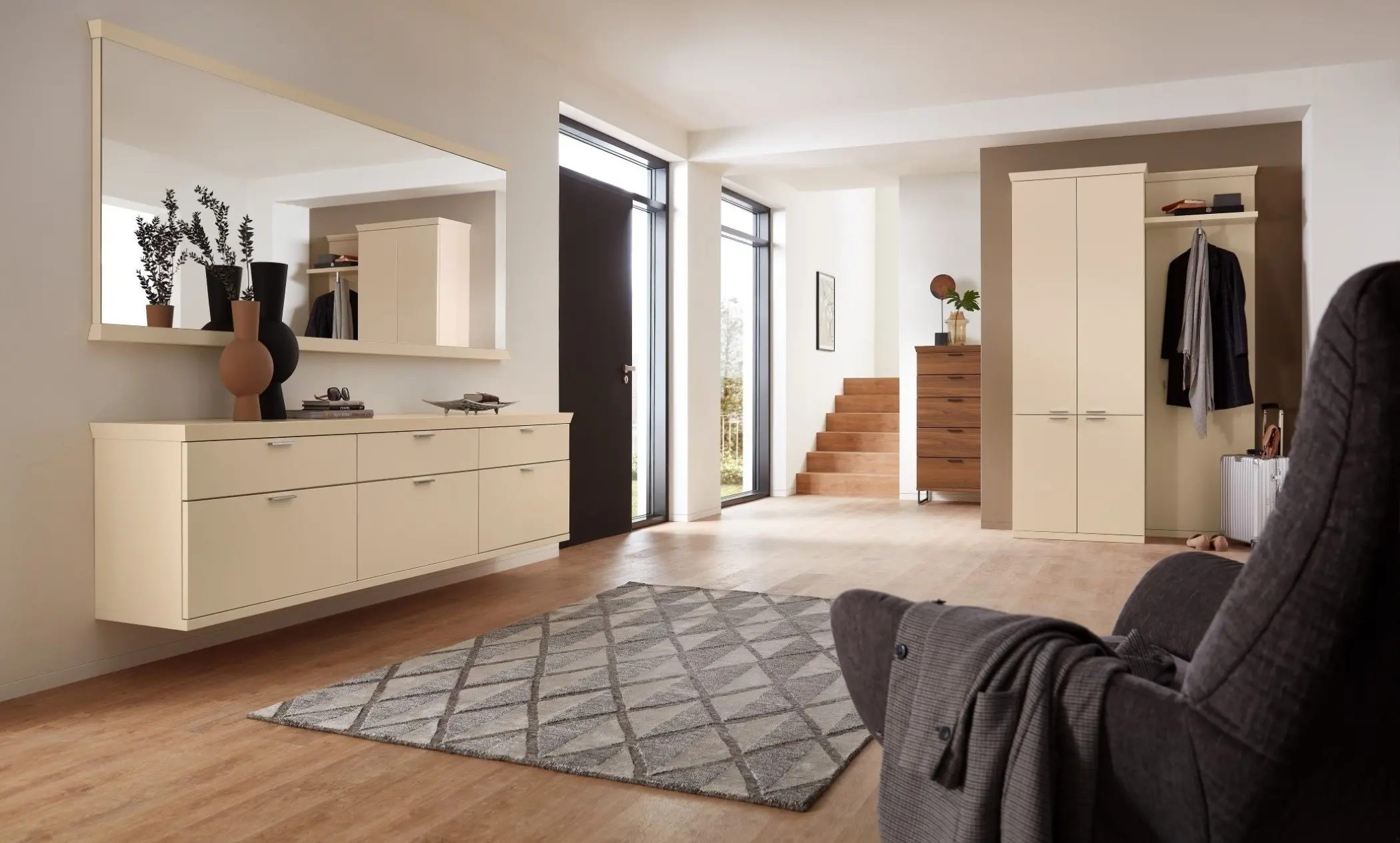 Sie sehen eine cremfarbene Garderobe mit viel Stauraum für Schuhe und Kleidung mit großem Spiegel